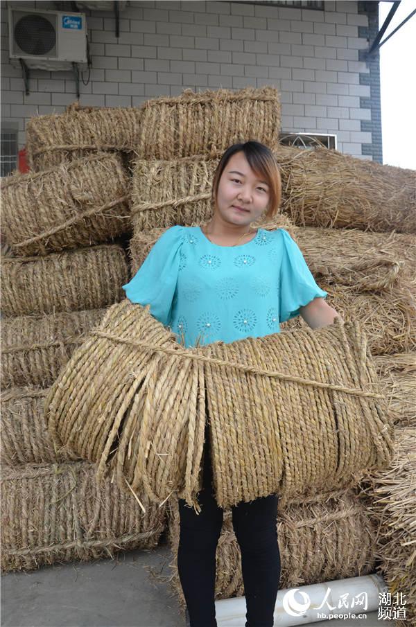 稻草加工戶曉月月為客商抱草繩上車。